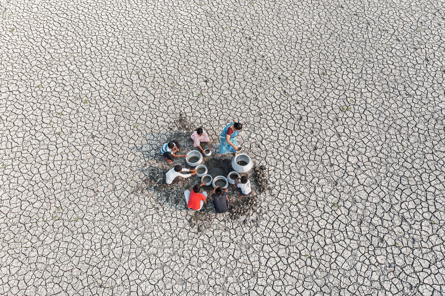 A group of local people collecting drinking water from a dried riverbed in Purulia, West Bengal, India.