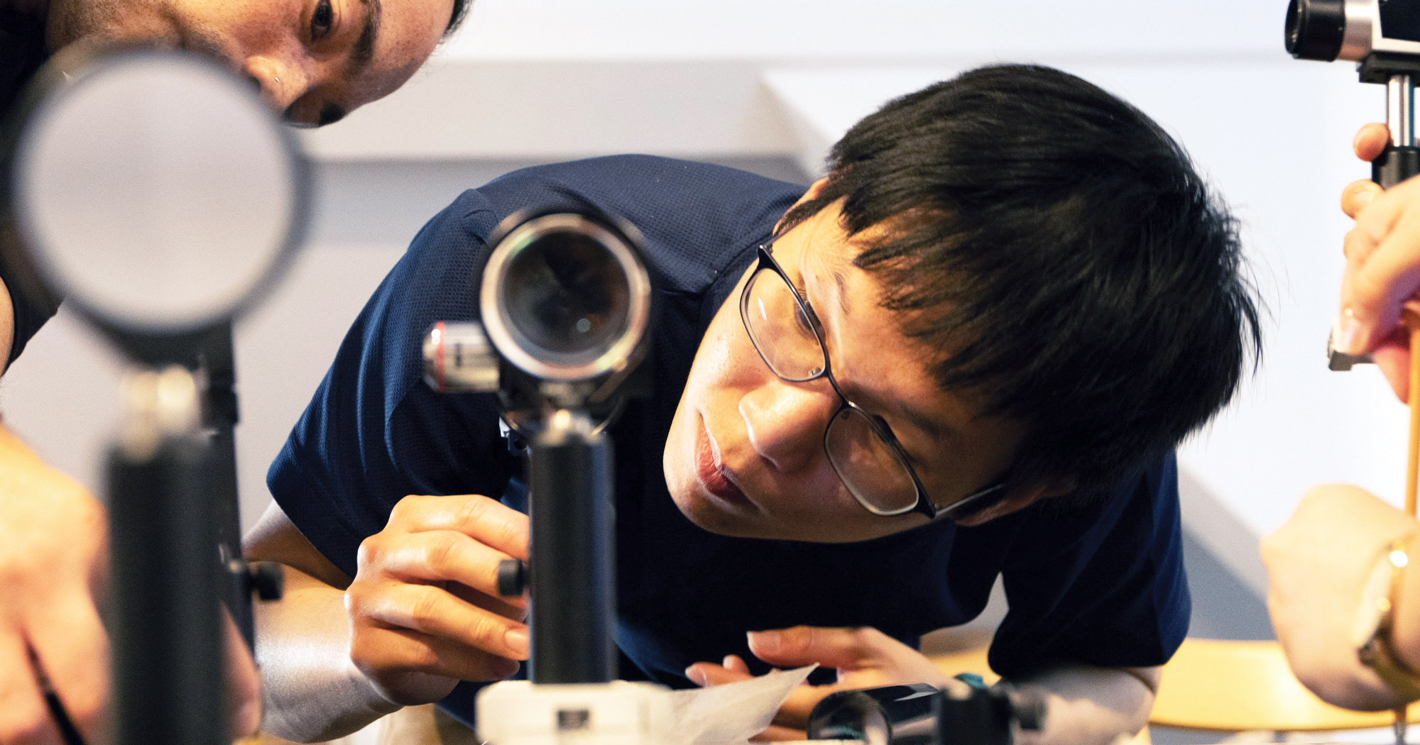 A photo of a student looking into a benchtop microscope.