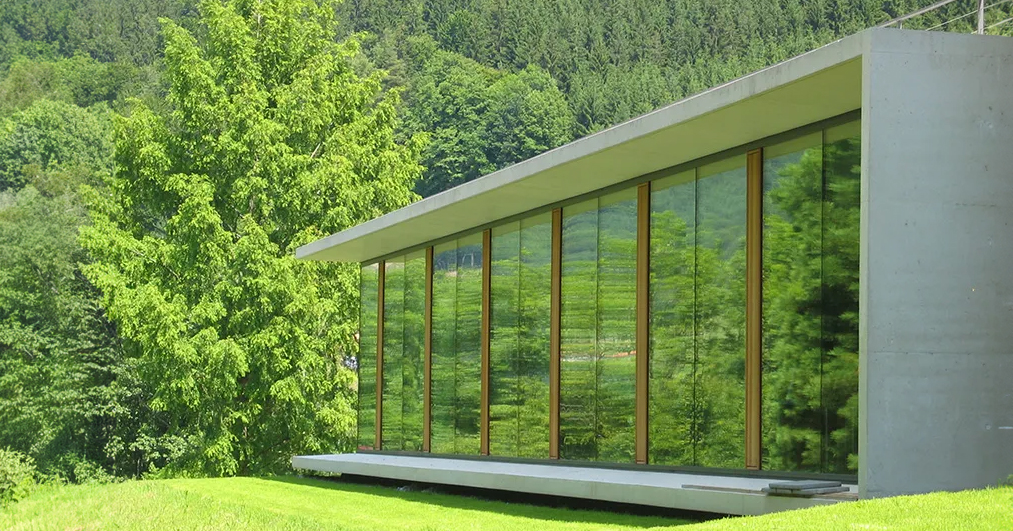 A photo of the north side library extension at the Mathematisches Forschungsinstitut Oberwolfach (MFO, Oberwolfach Research Institute for Mathematics) showing a mostly glass building in a green landscape.