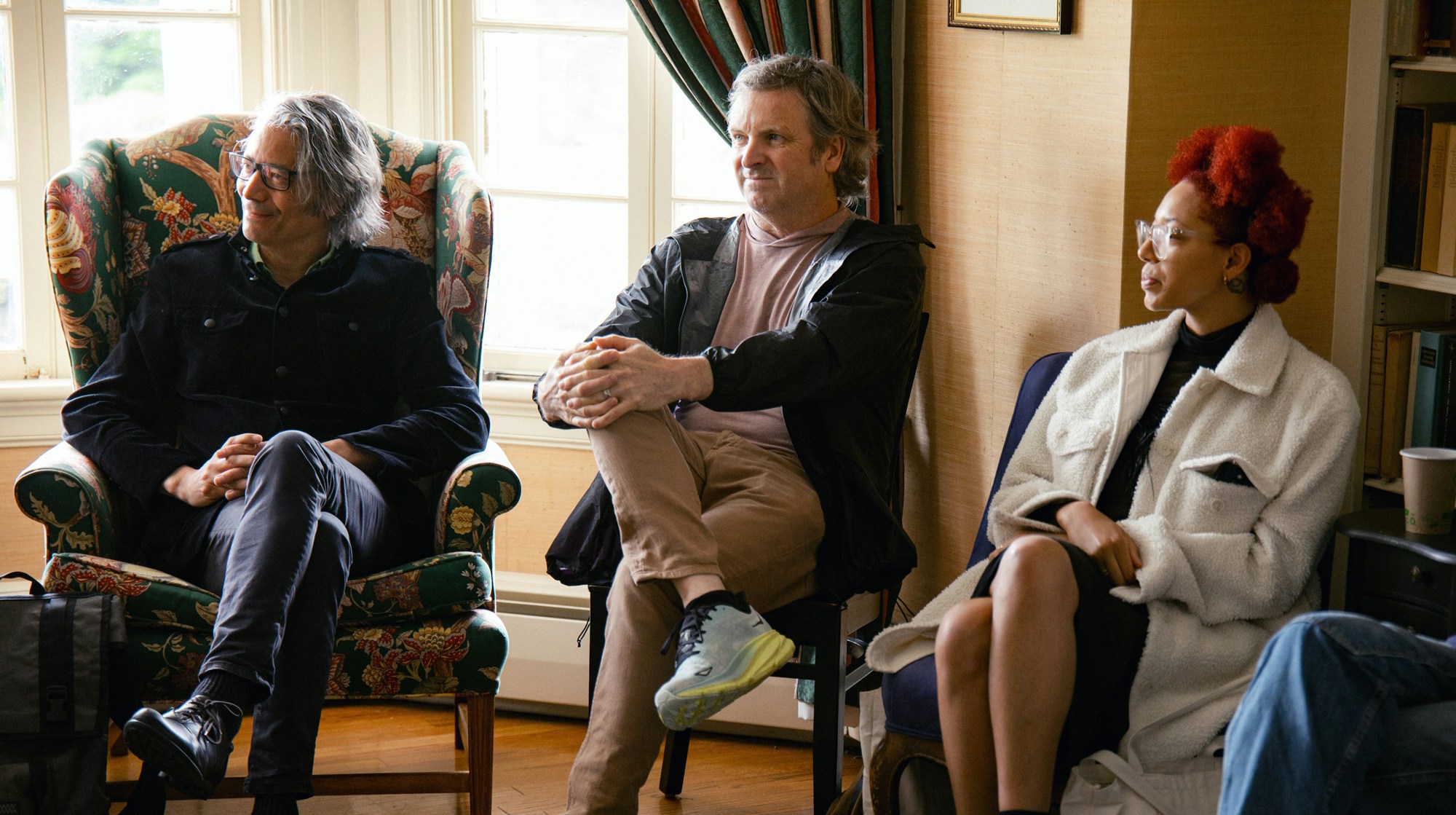 Three people sitting on chairs and participating in a group discussion.